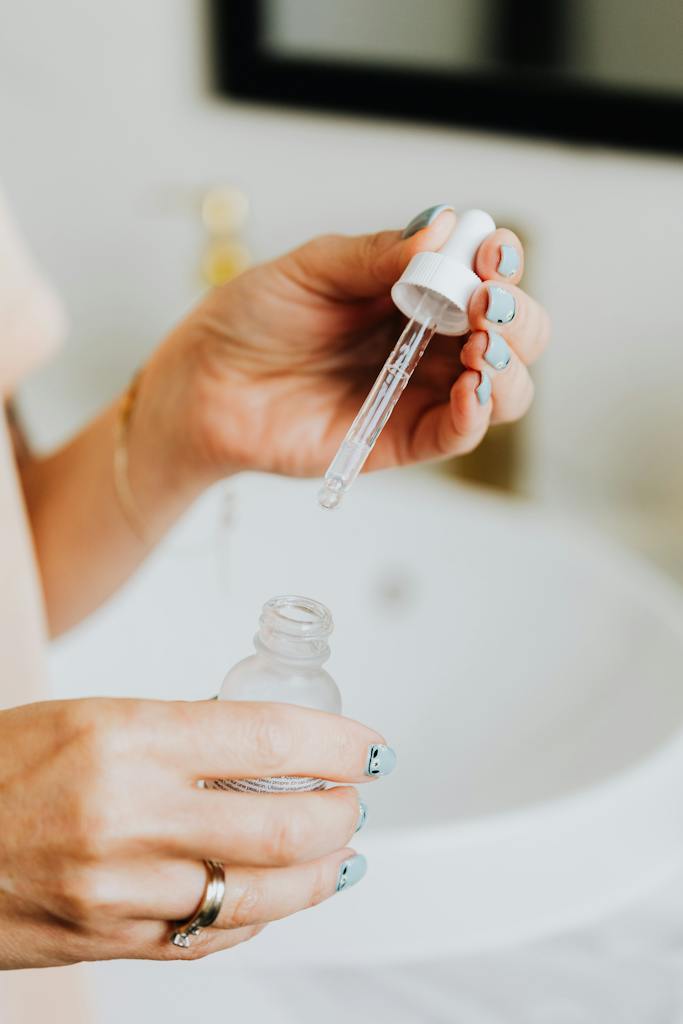 Person Holding Clear Glass Bottle